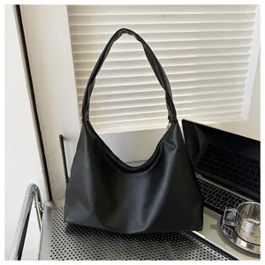 Detail of minimalist black PU leather tote bag on a metallic desk in a modern office setting