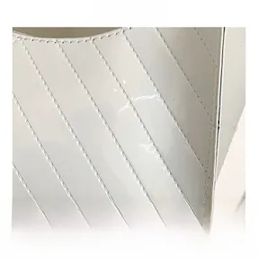 Close-up of glossy white patent leather handbag with precision diagonal stitching detail
