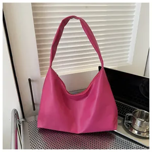 Vibrant hot pink hobo shoulder bag placed on a minimalist desk next to a laptop