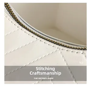 Detail view of precise white stitching and gold zipper on patent leather square bag