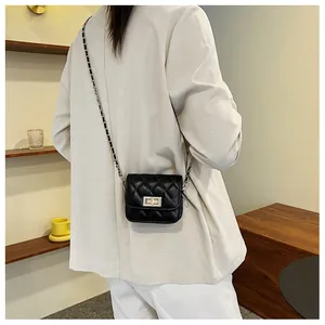 Schwarze Stepptasche mit goldener Kette, getragen zu einem beigen Blazer-Anzug