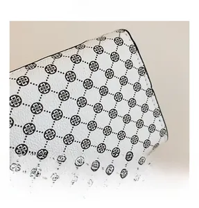 Macro detail of white leather shoulder bag with black clover patterns and lychee texture