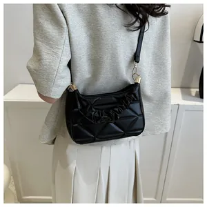Detail der schwarzen Stepptasche mit gerafftem Wolkengriff und goldener Hardware am Modell