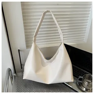 Close-up of cream faux leather hobo shoulder bag in a modern office desk setting