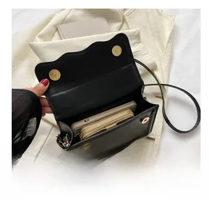 Internal capacity of the black square crossbody bag showing phone and wallet storage