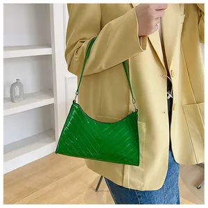 Detailed macro view of the emerald green crocodile pattern glossy faux leather handbag
