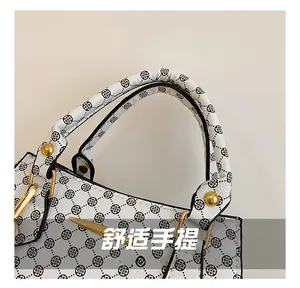 Detail of white leather handbag handle with black clover pattern and gold metal hardware