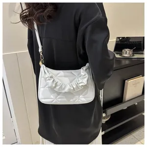 Detailansicht einer weißen geometrisch gesteppten Umhängetasche mit Rüschen am Model