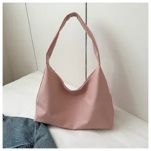 Close-up of a matte pink crescent shoulder bag with wide strap on a clean background