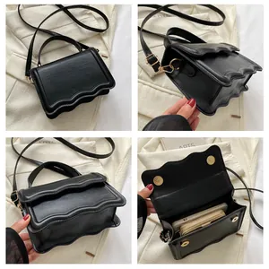 Detail of black wave-edged shoulder bag with gold magnetic clasp and adjustable strap