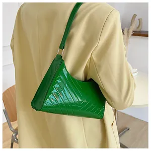 Detail of green patent leather underarm bag with V-shaped quilted texture and metal buckle