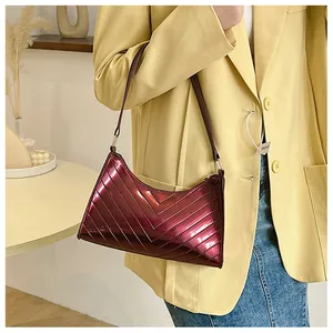 Detail of burgundy glossy patent leather underarm bag featuring elegant V-shaped quilting