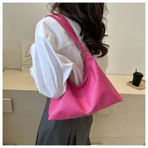 Detailed view of bright pink PU leather crescent bag worn by a model in a modern room
