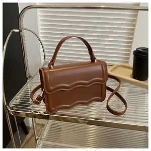 Close-up of caramel brown handbag featuring wave pattern layered flap and gold hardware