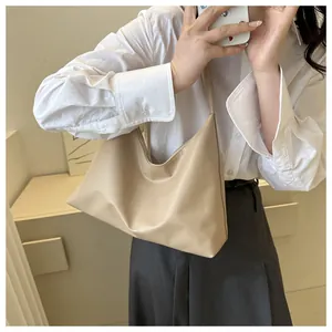 Close-up of minimalist beige faux leather shoulder bag with smooth matte texture