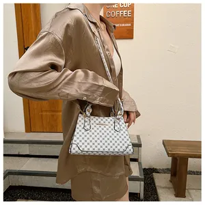 Close-up of a white leather bag with black dot pattern and elegant gold metal bar detail