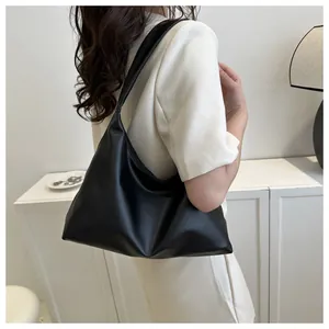 Minimalist black faux leather shoulder bag worn by model in a clean white setting