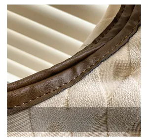 Détail du sac avec tissu texturé beige et coutures précises sur le cuir marron