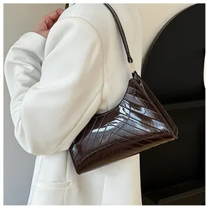 Detail of a deep brown glossy patent leather shoulder bag with V-shaped quilting texture