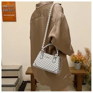 Polka dot handbag with gold hardware and long shoulder strap worn by a female model