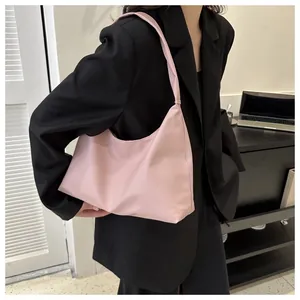 Detail of a light pink hobo bag in nylon material carried by a model in a black suit