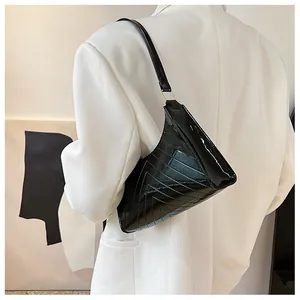 Detail of black glossy triangular underarm bag with V-shaped quilting and silver hardware