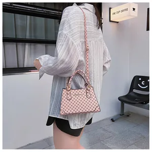Detail shot of a pink geometric pattern handbag worn by a model in a street style setting