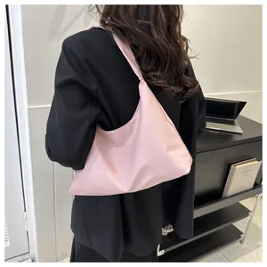 Detail view of the pink crescent shoulder bag on a model wearing a black blazer