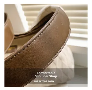 Gros plan d'une bandoulière en cuir marron avec surpiqûres sur un sac cabas matelassé