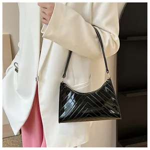 Macro shot of black glossy chevron quilted shoulder bag with slim strap and metal hardware