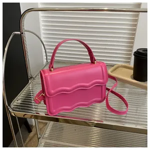Detail of rose pink handbag featuring double wavy edges and adjustable golden buckle