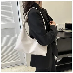 Detail of white leather shoulder bag with seamless strap on a black blazer outfit