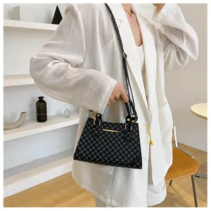 Polished lady carrying a geometric patterned crossbody handbag over white suit