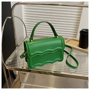 Detail of bright green square bag with wave-edge flap and golden metal hardware