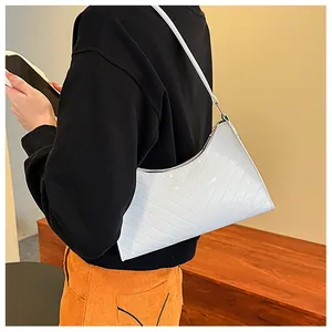White glossy patent leather underarm bag with V-shaped quilting shown on a female model