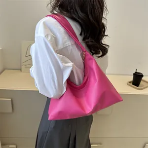 Chic fuchsia hobo shoulder bag with wide strap, worn by a model in a cozy home setting