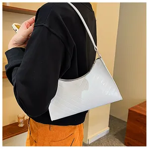 Close-up of white glossy patent leather shoulder bag with chevron quilted texture and strap
