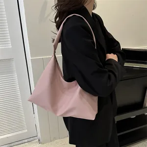Chic pink hobo tote bag in silky fabric worn by model in black suit for daily commute