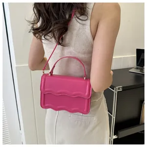 Detail of fuchsia square handbag featuring wavy edge design and gold-tone hardware