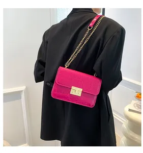Detail showing fuchsia crocodile pattern leather bag with golden chain and clasp lock