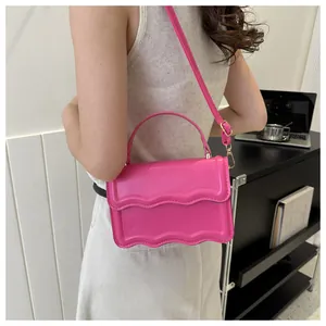 Detail of fuchsia flap bag featuring scalloped edges and gold-tone hardware