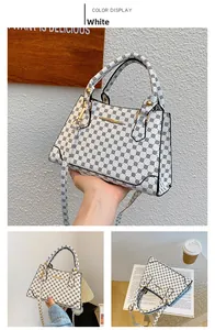 Close-up of a white tote bag featuring black geometric patterns and metal handles