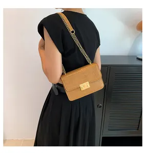 Detail of a brown crocodile pattern shoulder bag with a gold square lock and chain strap