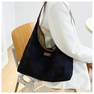 Détail d'un sac cabas en toile matelassée noire avec des finitions en cuir marron