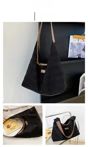 Détail d'un sac cabas noir matelassé avec anses en cuir marron et logo en métal