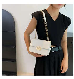 Detail of white crocodile pattern leather bag with gold buckle and chain strap