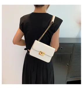 Detailed view of white crocodile pattern shoulder bag with gold chain strap on model