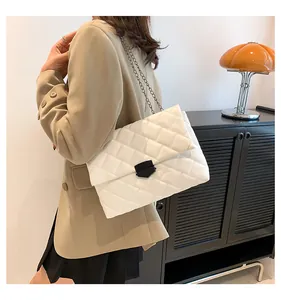 Detailansicht der weißen Stepptasche mit schwarzer Metallschnalle und Kettenriemen am Modell