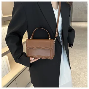 Brown scallop flap handbag with wavy edge detailing and gold hardware on model