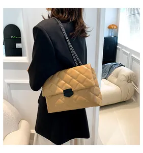 Detail der senfgelben gesteppten Handtasche mit schwarzer Schnalle und Silberkette